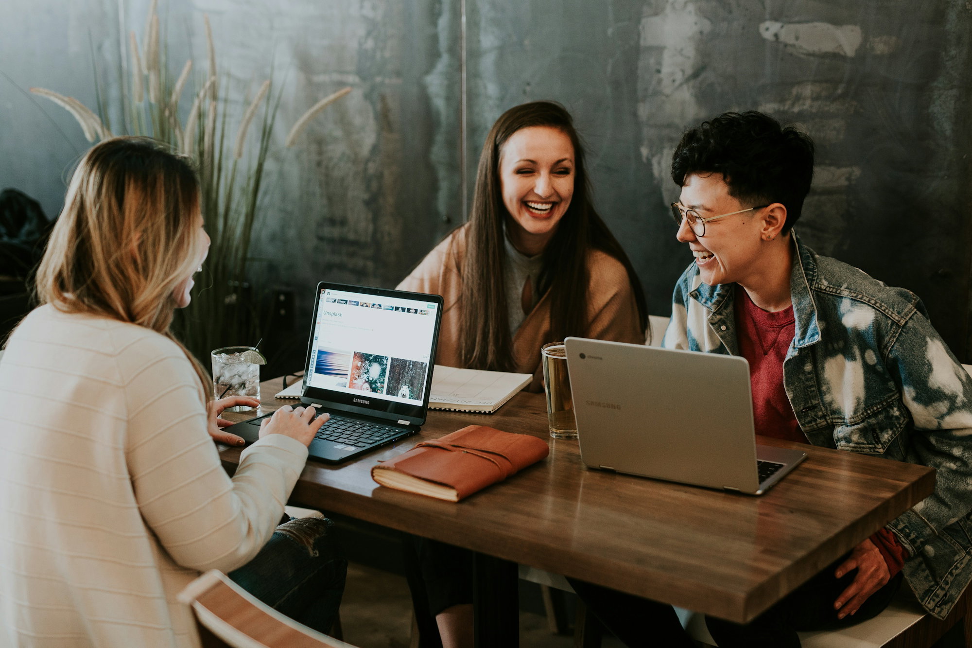 Three people sitting at a table laughing together during a workshop